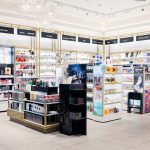 Przejrzysta ekspozycja kosmetyków do makijażu i pielęgnacji w salonie Douglas; rzędy podświetlanych regałów z produktami premium.