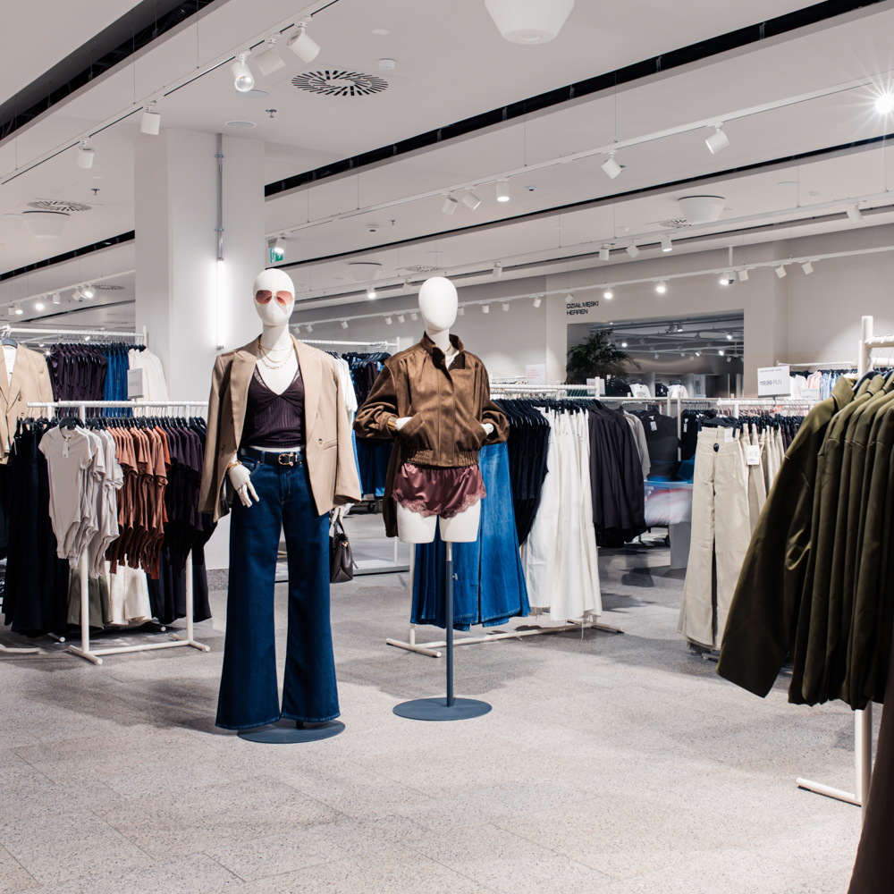 Przestronne wnętrze sklepu H&M w CH Galaxy z manekinami w modnych stylizacjach oraz rzędami ubrań na wieszakach.