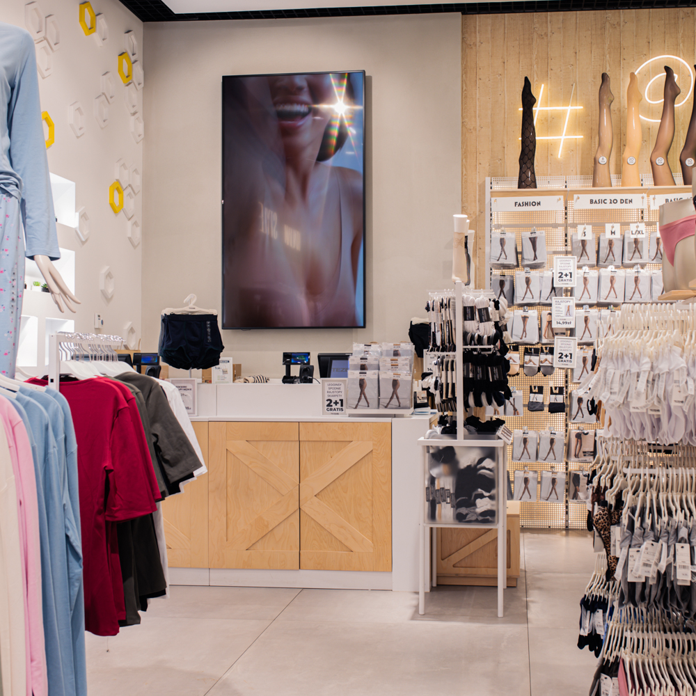 Nowoczesna strefa kasowa w salonie Tezenis w Centrum Galaxy, obok której znajduje się stand z szerokim wyborem rajstop w różnych wzorach.