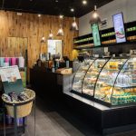 Przeszklona witryna z ciastami, kanapkami i przekąskami obok lady kasowej w kawiarni Starbucks w Centrum Galaxy.