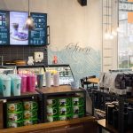 Regał w kawiarni Starbucks prezentujący kolekcję kultowych kubków oraz tumblerów. W tle widać fotele dla gości.