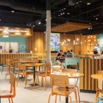 Nowoczesne i kolorowe wnętrze restauracji Popeyes w Centrum Galaxy z charakterystycznymi pomarańczowymi akcentami i grafikami nawiązującymi do Luizjany.