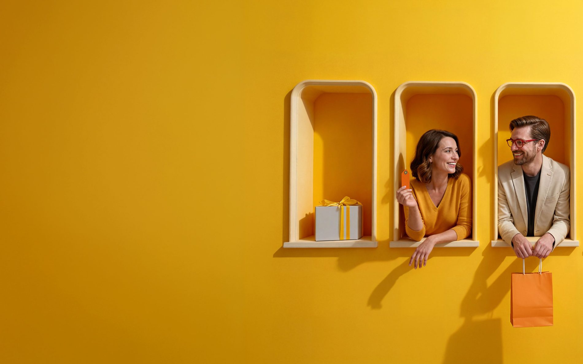 Para uśmiechniętych osób w żółtych okienkach ściany trzyma kartę płatniczą i torbę zakupową, obok ustawione są torba i zapakowany prezent.