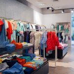 Zdjęcie przedstawia wnętrze sklepu United Colors of Benetton, na wieszakach widać różnego rodzaju odzież, w różnych kolorach.