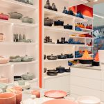Wnętrze sklepu Le Creuset prezentujące szeroki wybór kolorowych akcesoriów kuchennych, form do pieczenia i naczyń kamionkowych.