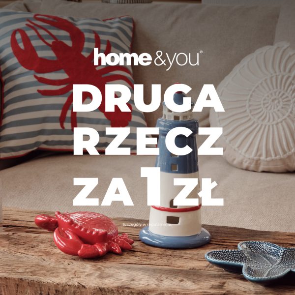 Dekoracje marynistyczne home&you: poduszka z homarem i latarnia morska na drewnianym stole. Informacja o promocji Druga rzecz za 1 zł.