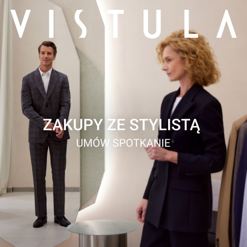 Klient w dopasowanym garniturze stoi przed lustrem podczas konsultacji ze stylistką w salonie mody; widoczny napis zachęcający do umówienia spotkania.