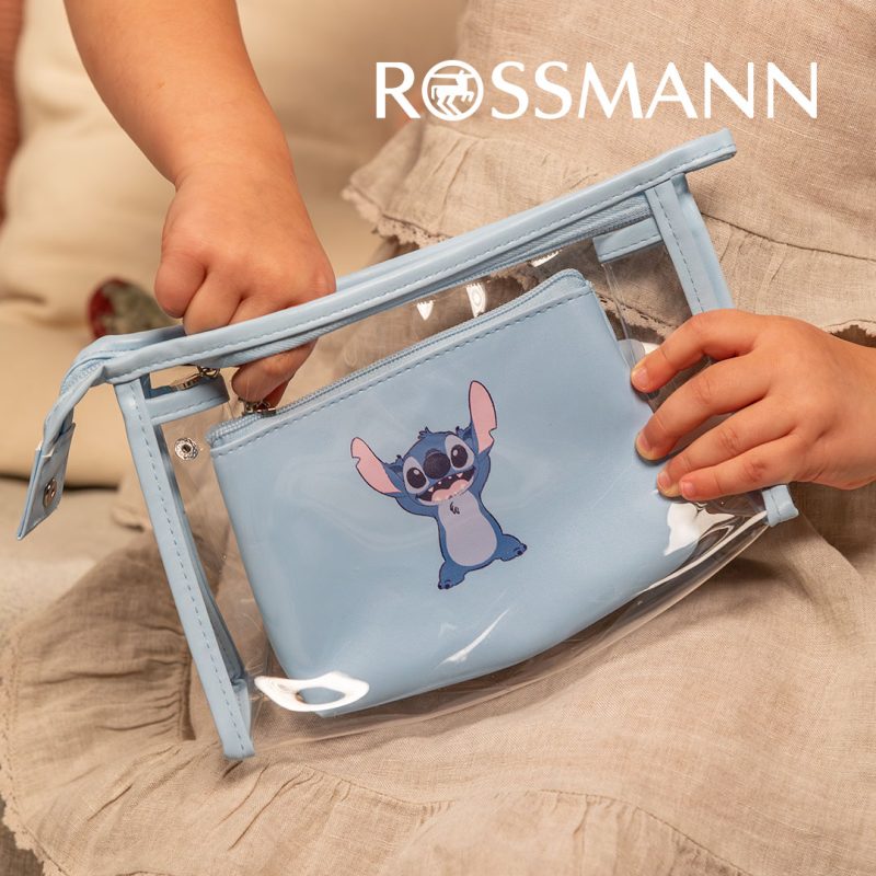 Grafika reklamowa drogerii Rossmann przedstawia dziecko trzymające w dłoniach błękitną, przezroczystą kosmetyczkę z motywem postaci Stitcha. W środku znajduje się mniejsza, dopasowana saszetka, a w prawym górnym rogu kompozycji widnieje białe logo marki Rossmann.