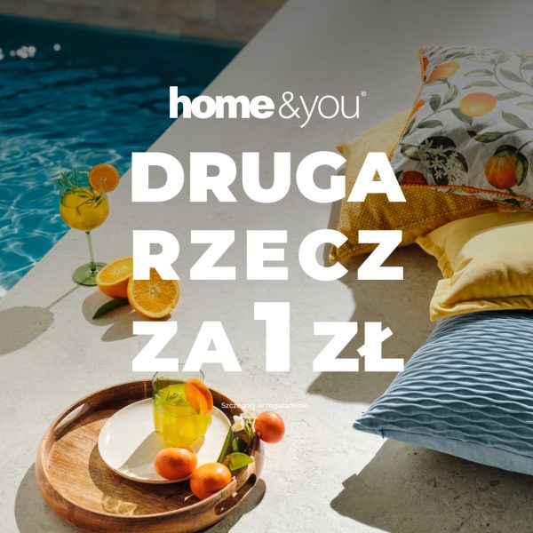 Promocyjna grafika home&you nawiązująca do wakacyjnego wypoczynku. Na zdjęciu widoczne są dekoracyjne poduszki, drewniana taca z napojem i owocami oraz basen w tle. Centralnie umieszczono komunikat o promocji „Druga rzecz za 1 zł”.