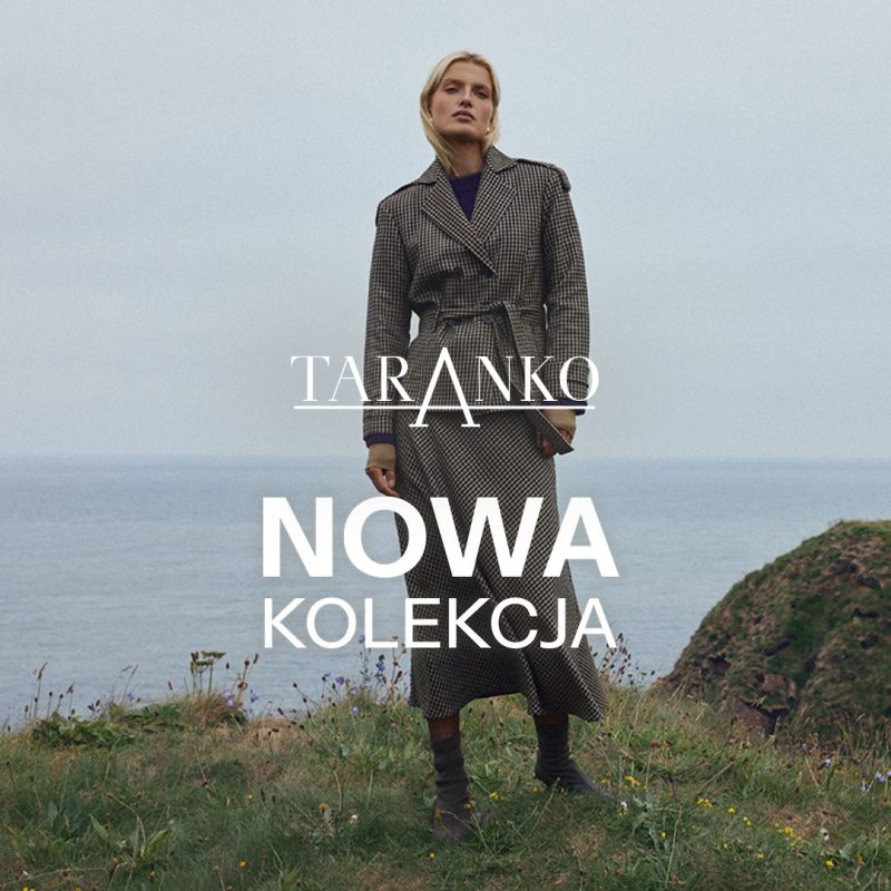 Kwadratowe zdjęcie wizerunkowe marki Taranko przedstawiające blond modelkę w długim, dwurzędowym płaszczu w kratkę standing na trawiastym klifie nad morzem. Na środku umieszczono białe logo TARANKO oraz duży biały napis NOWA KOLEKCJA.