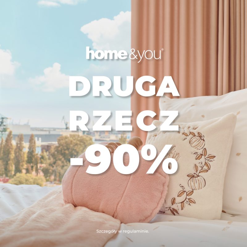 Kwadratowa grafika promocyjna marki home&you. Przedstawia przytulny kadr sypialni z łóżkiem usłanym białą pościelą z małym wzorem, różowym kocem oraz ozdobnymi poduszkami w kształcie dyni i z haftem. Za łóżkiem widoczne jest okno z widokiem na panoramę miasta oraz różowa zasłona. Na środku umieszczono białe logo home&you oraz duży biały napis DRUGA RZECZ -90%. Na dole drobny tekst Szczegóły w regulaminie.