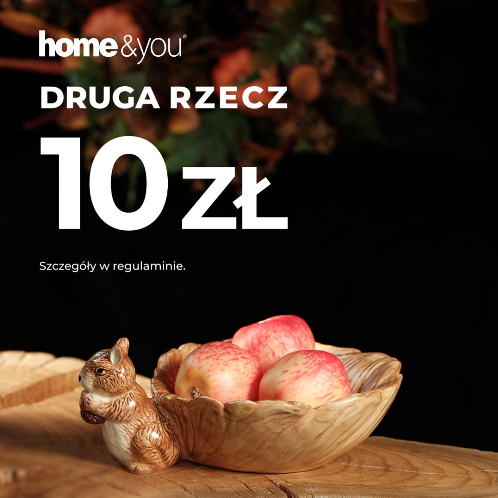 Elegancka kwadratowa grafika promocyjna marki home&you na ciemnym tle. W górnej części widnieje białe logo home&you, pod nim duży biały napis DRUGA RZECZ 10 zł oraz mały napis Szczegóły w regulaminie. W dolnej części na drewnianym blacie przedstawiono ceramiczną miseczkę w kształcie liścia z figurką wiewiórki trzymającej orzech, wypełnioną czerwonymi jabłkami.