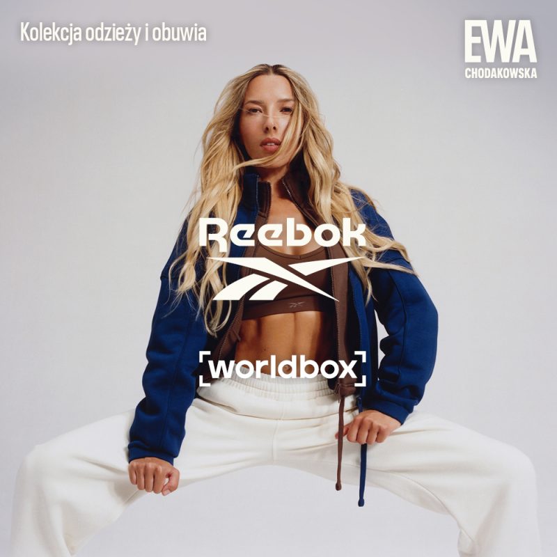 Kwadratowa grafika reklamowa marki WORLDBOX przedstawiająca Ewę Chodakowską w sportowej stylizacji. Modelka ma długie blond włosy i pozuje w brązowym topie, rozpiętej granatowej bluzie dresowej oraz jasnych waniliowych spodniach dresowych. W lewym górnym rogu znajduje się biały napis Kolekcja odzieży i obuwia, w prawym górnym logo EWA CHODAKOWSKA, a w centrum grafiki nałożone na siebie białe logo marki Reebok oraz fioletowo-białe logo WORLDBOX.