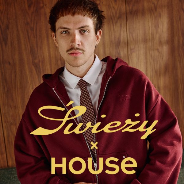 Kwadratowa grafika promocyjna marki House. Na zdjęciu widnieje Bartek „Świeży” Laskowski w bordowej rozpinanej bluzie z kapturem, białej koszuli i krawacie na tle drewnianej ściany. Na pierwszym planie umieszczono stylizowany żółty napis Świeży x HOUSE.