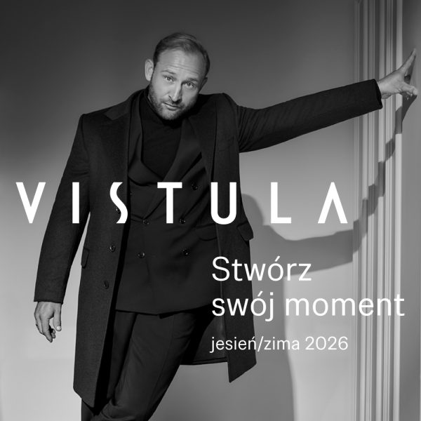 Czarno-białe zdjęcie wizerunkowe marki Vistula przedstawiające mężczyznę w eleganckim, ciemnym płaszczu, dwurzędowej marynarce i golfie, opierającego się dłonią o jasną ścianę. Na grafice znajduje się duże, białe logo „VISTULA” oraz napis „Stwórz swój moment jesień/zima 2026”.