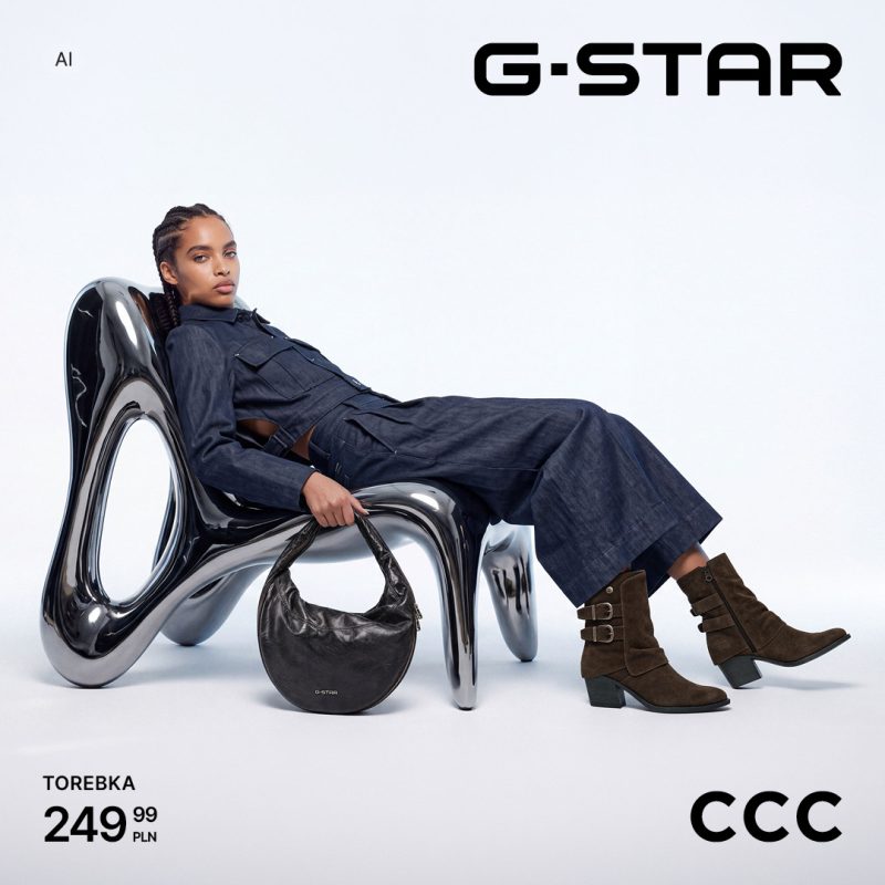 Modelka w ciemnym komplecie denimowym oparta o designerski fotel, prezentująca pojemną czarną torebkę G-Star za 249,99 zł i zamszowe buty w salonie CCC w CH Galaxy Szczecin