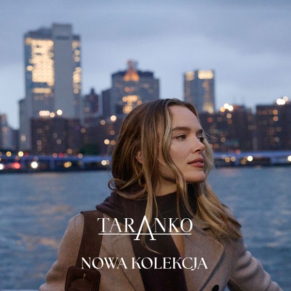 Elegancka grafika promocyjna nowej kolekcji marki Taranko w miejskim stylu. Na pierwszym planie widoczna jest młoda kobieta o jasnych włosach, ubrana w beżowy płaszcz i ciemną odzież, spoglądająca w prawą stronę. W dolnej części grafiki znajduje się biały napis z nazwą marki „TARANKO” oraz hasło „NOWA KOLEKCJA”. W tle rozciąga się panorama oświetlonego miasta z wieżowcami oraz tafla wody.